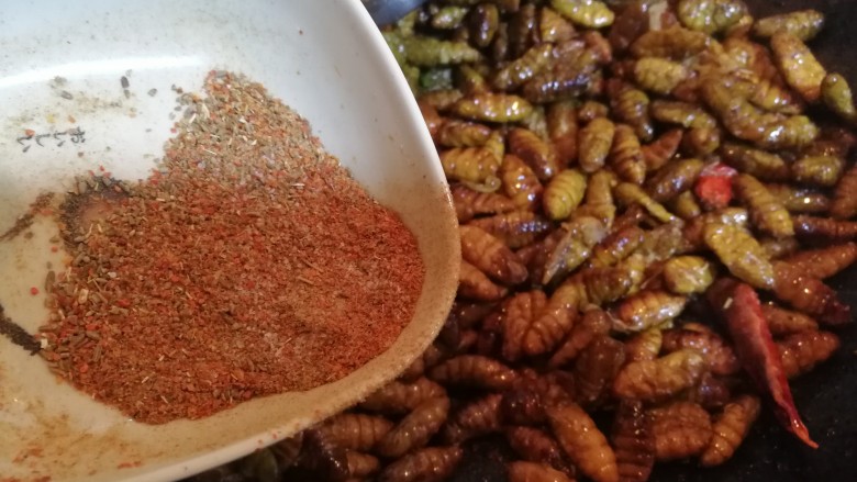 酥辣小蚕蛹,蚕蛹外皮炒制酥脆的时候。放入烧烤料，炒至入味儿。