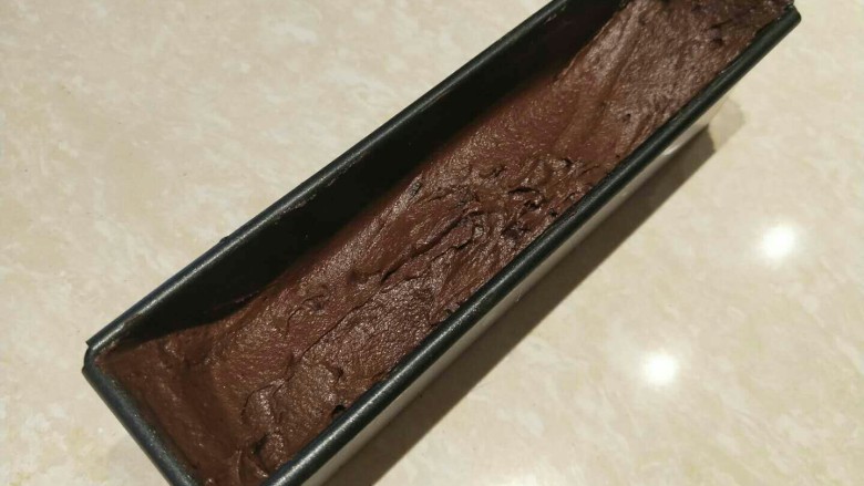 蔓越莓巧克力磅蛋糕,倒入模具，用刮刀抚平表面 注意两边高中间低