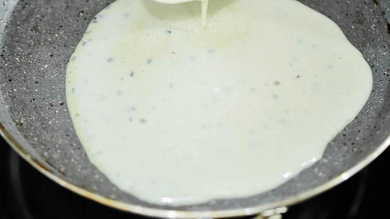 经典蛋卷,锅内温热时，倒入米糊，迅速晃动锅，让米糊均匀铺开。
