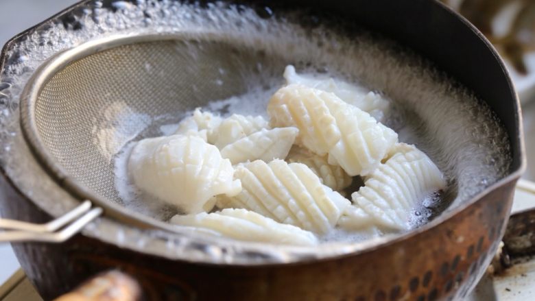 海鲜咖喱乌冬面,准备一锅清水，加入二片姜烧开，将切好的鱿鱼放入沸水中焯至卷曲变白捞出，焯鱿鱼的水留用。