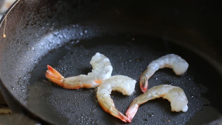 海鲜咖喱乌冬面,锅中加油烧热，放入剥好的虾煎至七成熟，变色卷曲，盛出待用。