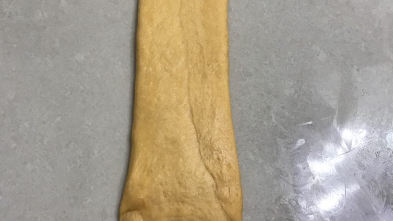 南瓜烫种炼乳吐司,15翻面再用擀面杖擀一下，整理成大约长30厘米，宽7厘米。
