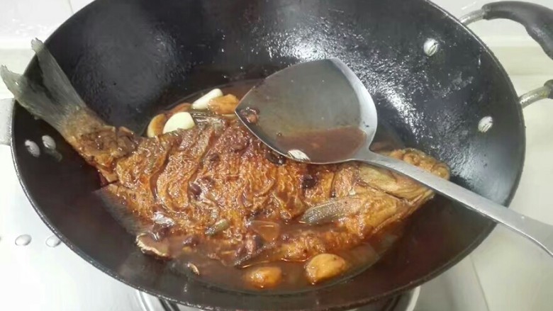 厨房挑战+荤菜+大蒜头黄豆酱烧鳊鱼,打开锅盖，大火收汁，用锅铲把鱼汤往鱼表面浇