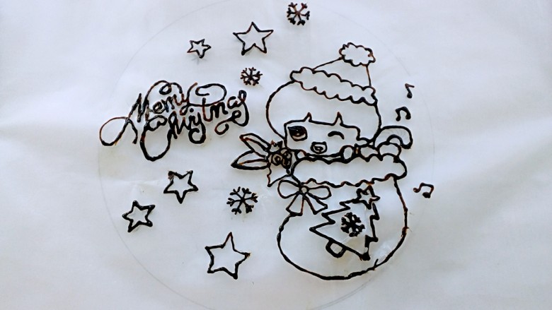 芝士转印圣诞蛋糕,用食用铅笔在糯米纸上画好图，底层放亚克力板，上面放糯米纸，用夹子固定好，用巧克力拉线膏勾勒出整个图案。