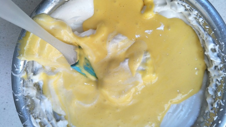 戚风纸杯蛋糕,先把三分之一的蛋清加入到蛋黄中画z字形拌均匀，接着把所有的蛋黄液倒入剩下的蛋清中。