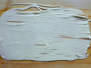 比葱油饼简单又好吃的盘丝饼,从最上面开始，用刀横着将面皮切成粗细均匀的细条。