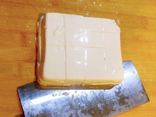 麻婆豆腐,右手把刀的侧面放在豆腐底部，左手轻扶豆腐表面，把豆腐从砧板上移到盘中