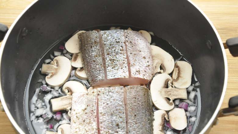 白葡萄酒蒸鲈鱼,把鱼块放在蘑菇片上，中火蒸煮约7、8分钟至鱼块熟后，轻轻取出鱼块并注意保温，留汤汁在锅里，继续调味；