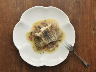 白葡萄酒蒸鲈鱼,盘中舀适量做好的调味汤汁，把保温好的鱼块放在汤汁里，美味的白葡萄酒蒸鲈鱼就OK啦~