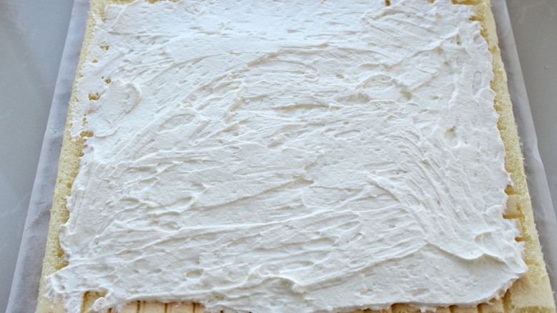 抹茶树桩蛋糕卷,将淡奶油涂抹在蛋糕胚的正面