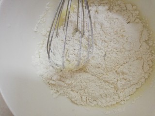 新手也能做的——柔软戚风蛋糕（8寸）,把过筛好的低粉倒入到牛奶混合液里，用z字手法拌匀。拌到没有看到白色颗粒就好。