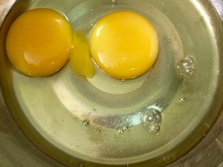 奶香玉米饼,在无水无油的盆里打入两个乌鸡蛋，我用的乌鸡蛋比较小，所以用了两个，如果用普通鸡蛋比较大，一个也是可以的。