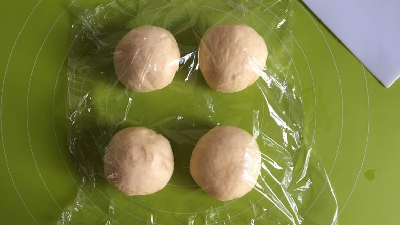 黄桃椰蓉心形面包,将面团均分为4个，揉圆，盖上保鲜膜松弛15分钟