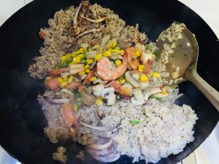蘑菇海鲜焗饭,将虾和玉米等倒入混炒均匀加盐或少许酱油