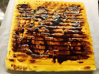 香橙蛋糕卷,出炉后，倒扣于烤网上。撕去油纸。涂上巧克力酱。