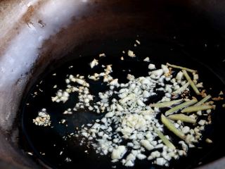 双椒炒鱿鱼卷,锅内放入适量的色拉油，放入蒜末、姜丝爆香；