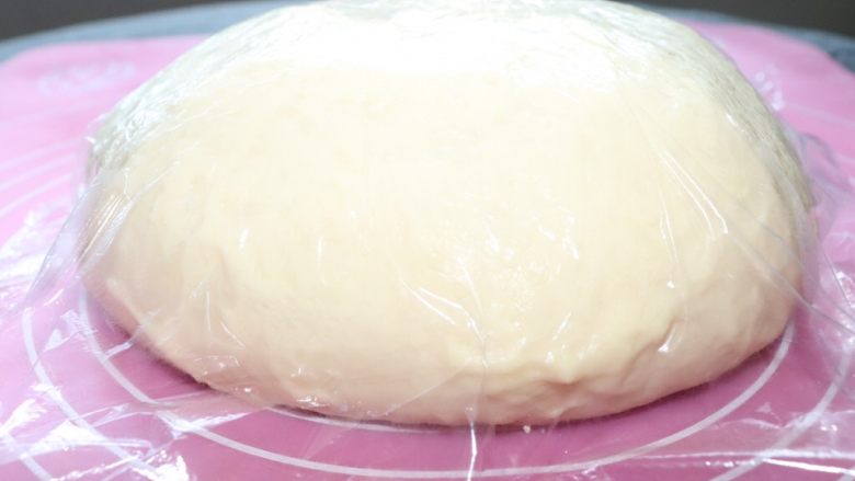 红豆沙面包圈,面团放在硅胶垫上揉圆，盖上保鲜膜，室温发酵到两倍大。