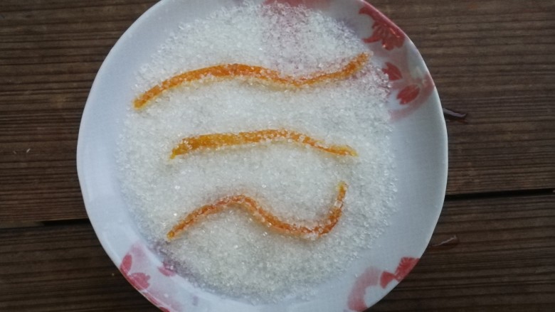 糖渍橙皮,盘子里倒适量白砂糖，放凉的橙皮依次在白砂糖里滚一圈，裹上一层砂糖