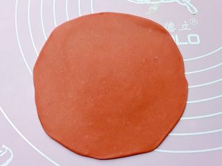 福袋馒头,将发酵好的面团分别排气揉匀后，取一红色面团擀成中间稍厚、四周薄的面皮。