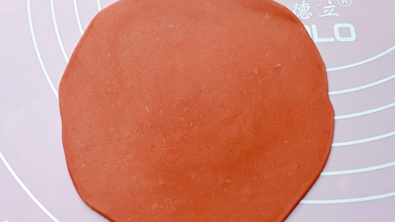 福袋馒头,将发酵好的面团分别排气揉匀后，取一红色面团擀成中间稍厚、四周薄的面皮。