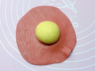 福袋馒头,取一黄色小面团搓成圆球，放在红色面皮中间。