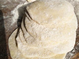 手工荠菜肉馅饺子,啦啦啦，这是制作好的饺子皮，可以撒上一些面粉，防止面皮粘在一起。
