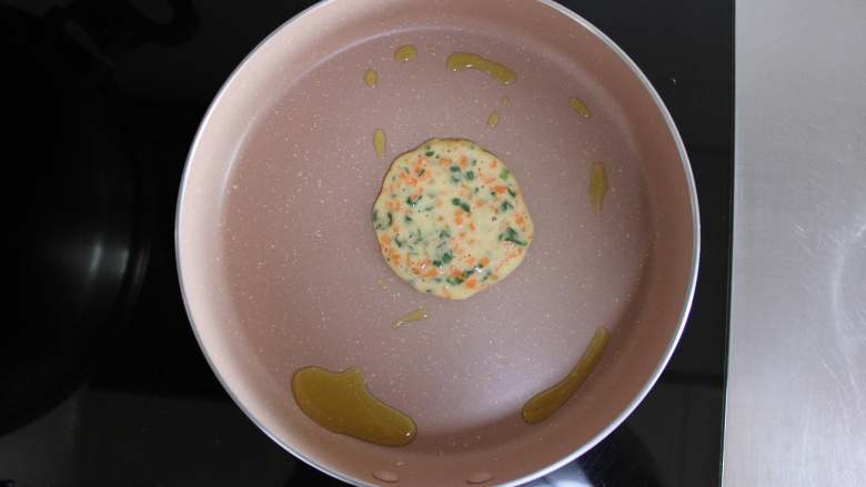 胡萝卜蛋饼（适合11个月龄以上宝宝）,锅里放入适量的核桃油，用勺子舀一勺面糊，摊成小饼