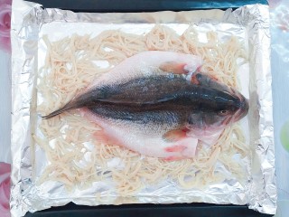 纸包烤鱼,接下来把腌制好的鲈鱼铺在放有金针菇的烤盘里！