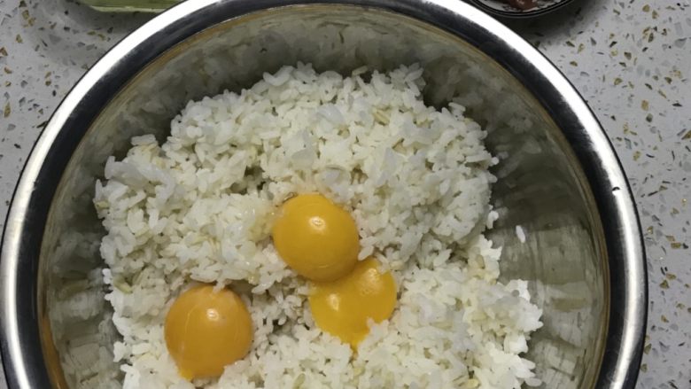 黄金蛋炒饭,所有材料备齐后，把蛋白和蛋黄分开，三颗蛋黄放入米饭中搅拌均匀，让每颗饭粒都沾满蛋液。
