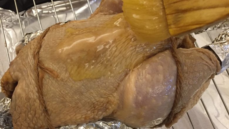 中国式圣诞节上的烤鸡,在鸡身均匀的涂抹上黄油蜂蜜混合液。