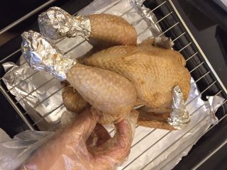 中国式圣诞节上的烤鸡,用锡纸包好小腿末及鸡翅尖，以防温度过高，烤焦。
