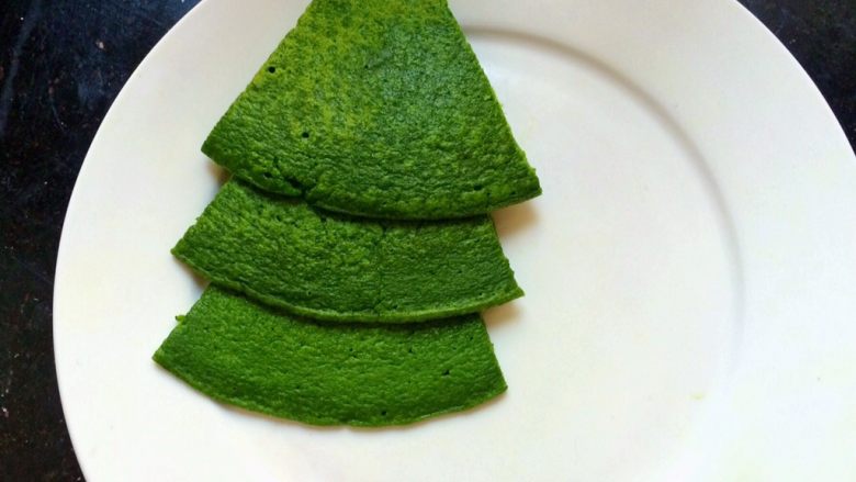 创意摆盘~雪中圣诞小树(椰蓉菠菜蛋饼),开始摆盘，取3块菠菜饼，从下往上叠，叠出树的造型