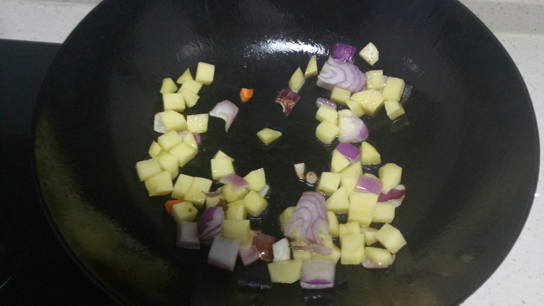 羊肉焖饭,锅中放入适量油，炒香洋葱里，放入土豆粒翻炒2分钟。