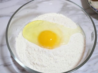 鸡蛋葱花饼,将1个鸡蛋磕入面粉中