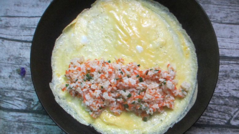 炒饭版肉松长棍面包,待蛋液即将凝固时，在蛋皮底部放入炒好的米饭