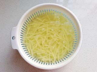 火腿土豆烘蛋,切好的土豆丝用清水冲洗后沥干备用；