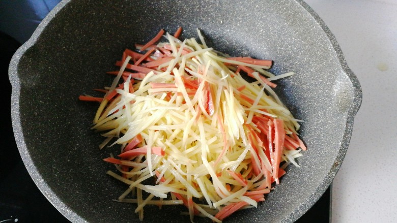 火腿土豆烘蛋,不粘锅中入少许油，放入火腿土豆丝先翻炒一下；