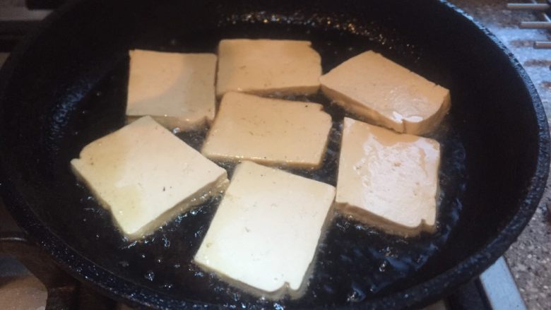 香辣西芹炒豆干,平底锅放烧热，放入豆腐片小火煎。