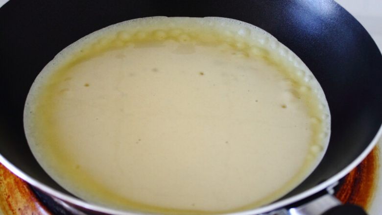 挪威薄煎饼Pannekake,5. 舀勺面浆到锅中，并晃满全锅；待四周翘起时翻面。