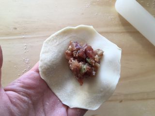 手工牛肉水饺,取出冰箱里的牛肉馅儿，用勺子舀一小勺到饺子皮中间