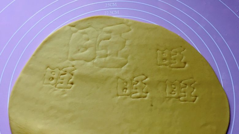 新年旺旺旺,然后取黄色面团擀成1cm厚的面片，用美工刀轻轻地刻写出一个大 “旺 ”、4个小 ”旺”的字样。
