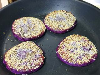 芝麻紫薯糯米饼,紫薯饼慢慢颜色变深，芝麻变金黄，可以翻面了，煎到同样程度就熟了，起锅。