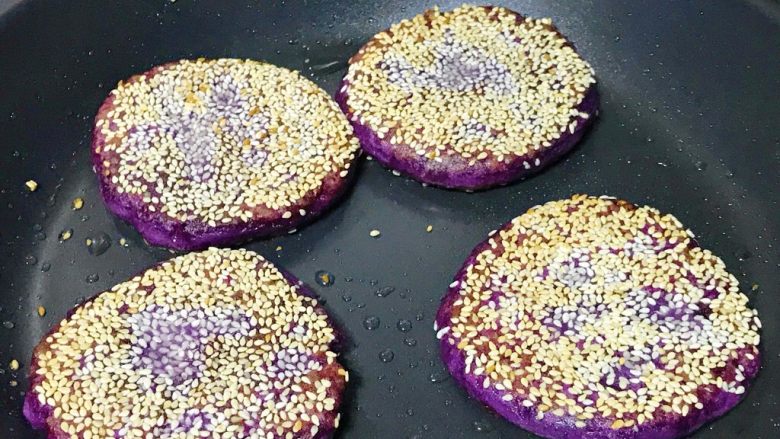 芝麻紫薯糯米饼,紫薯饼慢慢颜色变深，芝麻变金黄，可以翻面了，煎到同样程度就熟了，起锅。