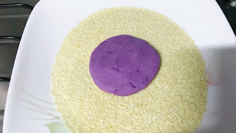 芝麻紫薯糯米饼,紫薯饼用力按向芝麻。