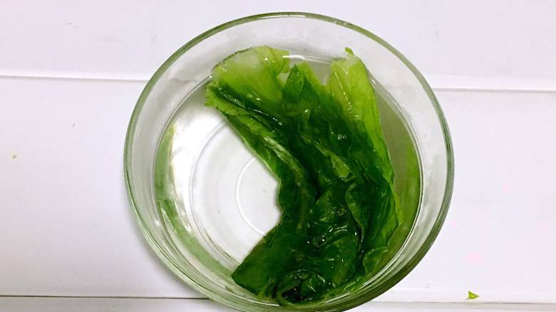 翡翠鳕鱼粥宝宝辅食,焯好的油麦菜捞出，放入冷水中冷却一下。

PS：  焯水后的蔬菜温度比较高，离水后与空气中的氧气接触容易产生热氧作用，营养素会流失。所以需要及时冷却降温，减少营养流失，还可以保持蔬菜翠绿的颜色。
