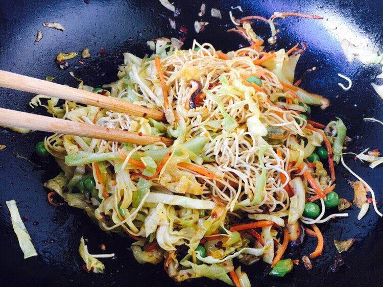 营养早餐 麻辣什锦炒面,用筷子拌匀面和蔬菜。