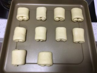 日式牛奶面包卷,卷好的面团放入烤盘，每一个面团之间要留空隙，喷壶喷上清水保湿，放入烤箱，发酵档发酵40分钟