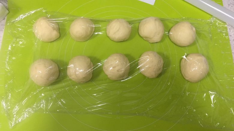 日式牛奶面包卷,取出面团按压排气后分割为10份，盖上保鲜膜松弛10分钟