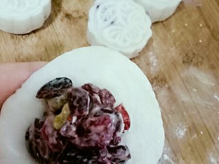 蔓越莓冰皮月饼♧,面皮压扁，包馅，团圆后放在熟糯米粉的案板上，月饼模内放入少量熟糯米粉，接下来压模了。