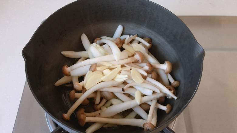 油浸蟹味菇拌烤茄子,放入蟹味菇和蒜片，中小火炒制